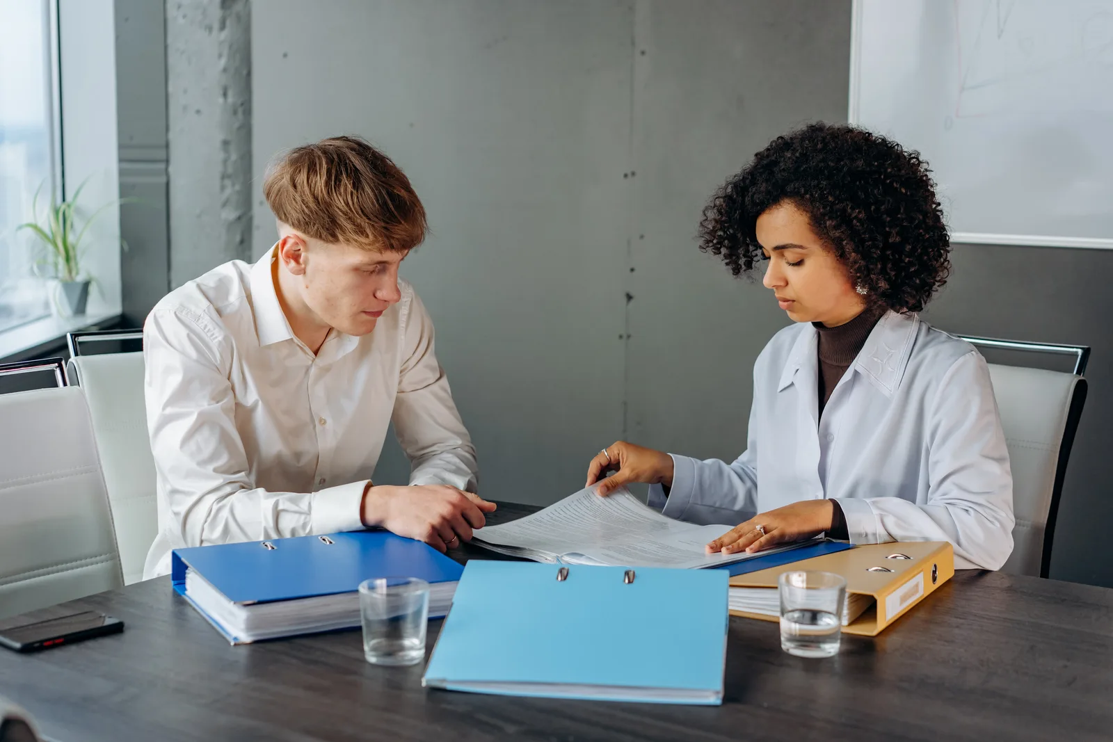 Two colleagues discussing important business documents at an office desk.