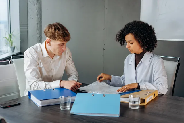Two colleagues discussing important business documents at an office desk. Business insurance return on investment: how to assess value