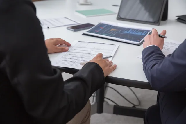 Close-up of professionals reviewing documents in an office setting, focused on analytics. A transparent method for reviewing business insurance, with declared limits and dated conclusions