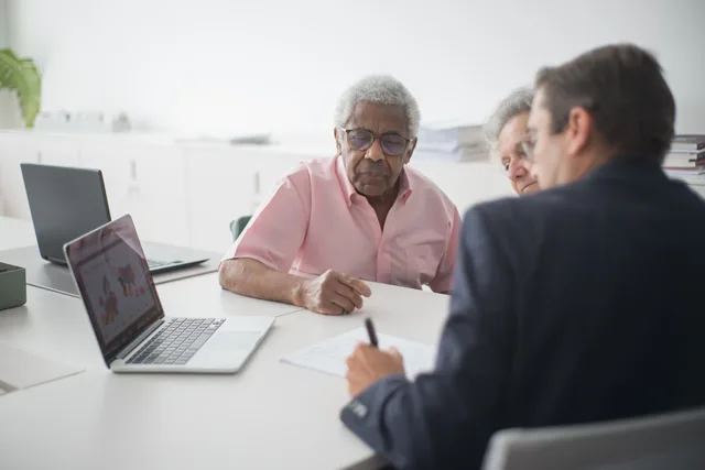 Senior couple discussing insurance options with a consultant in an office setting. Commercial insurance service standards from customer harm and capacity, with exceptions operated openly