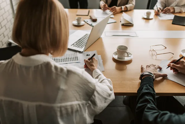 Corporate team discussing strategies at a desk with laptops and documents. A six-step insurance strategy framework, from exposure register to approved review